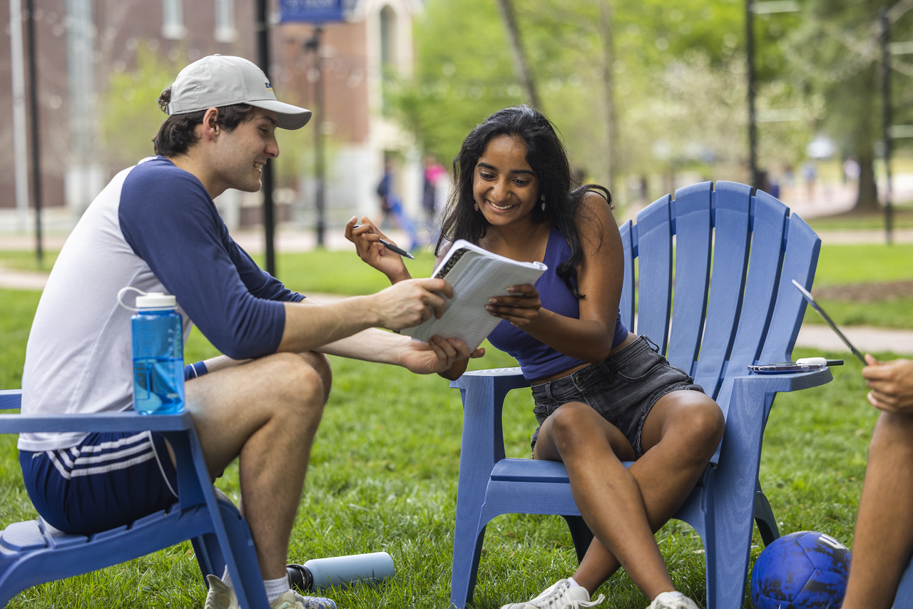 Three students on the Oxford quad using a laptop