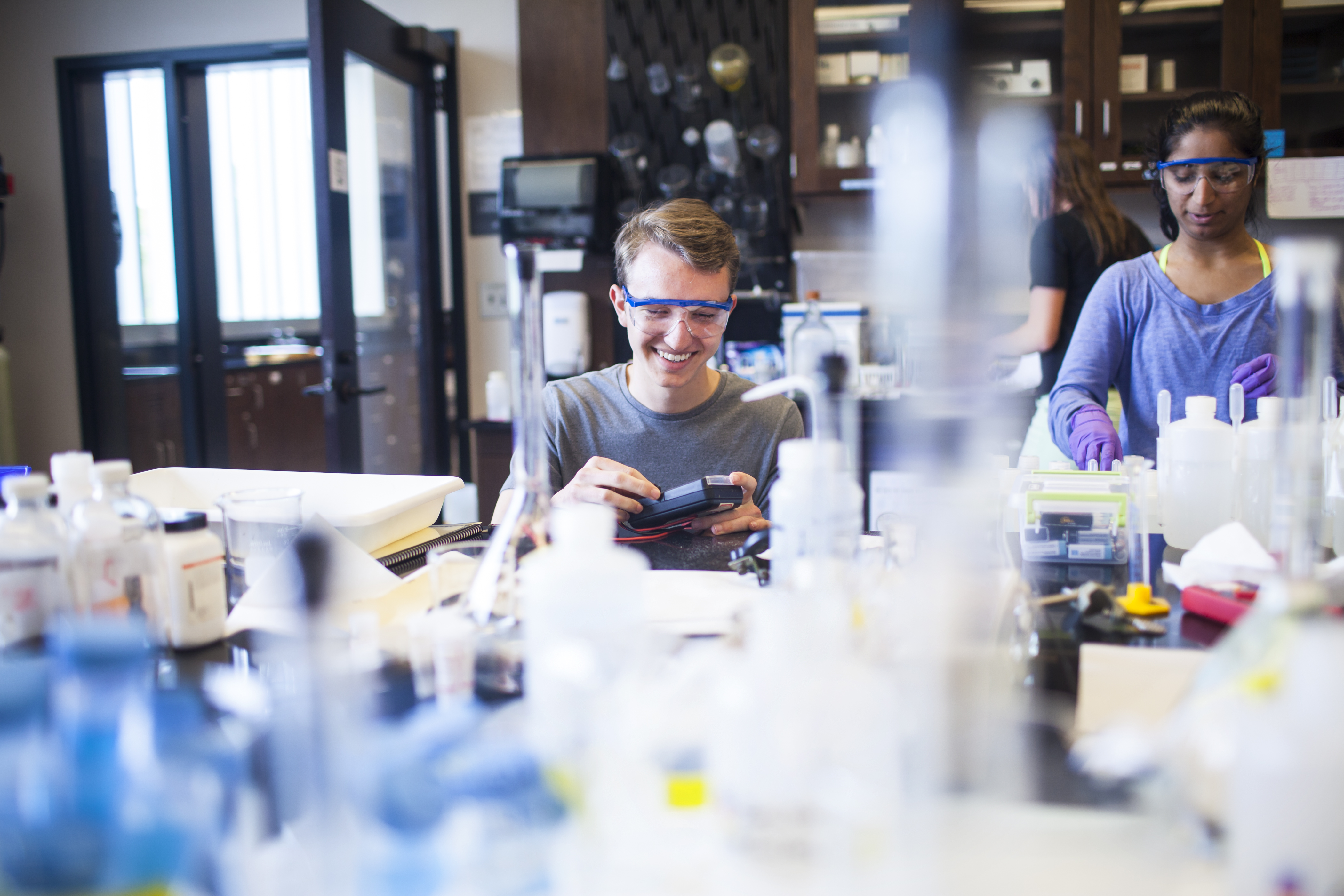 A professor assists two Oxford students in a classroom