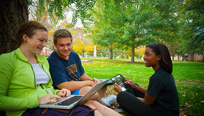 Three students on the Oxford quad using a laptop